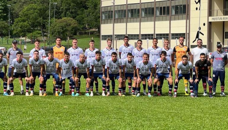 Um time de futebol está posando para uma foto do time em um campo.