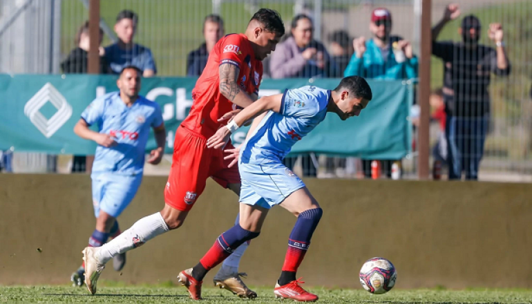 Dois jogadores de futebol estão jogando futebol em um campo.