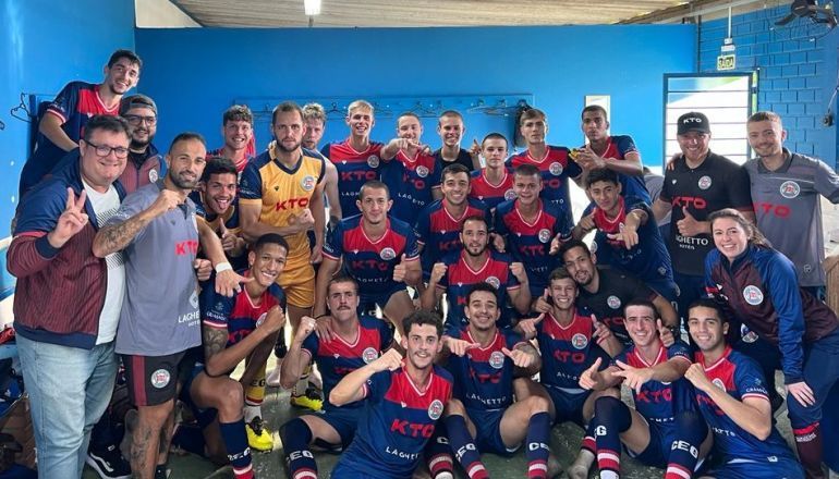 Um grupo de jogadores de futebol posa para uma foto em um vestiário.