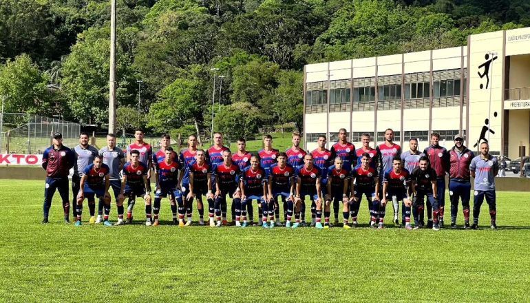 Um time de futebol posa para uma foto em um campo.