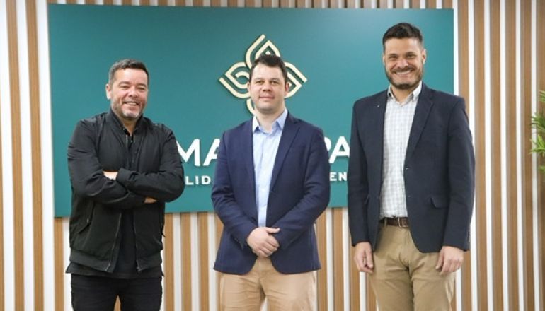 Três homens estão parados um ao lado do outro em frente a uma placa.