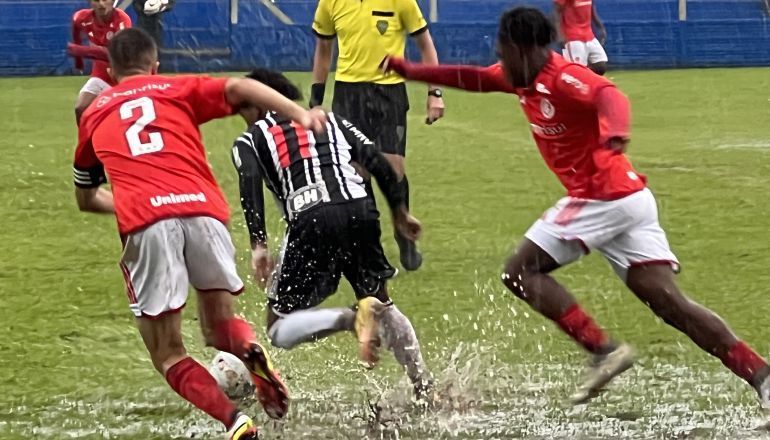 Um grupo de jogadores de futebol está jogando na chuva.