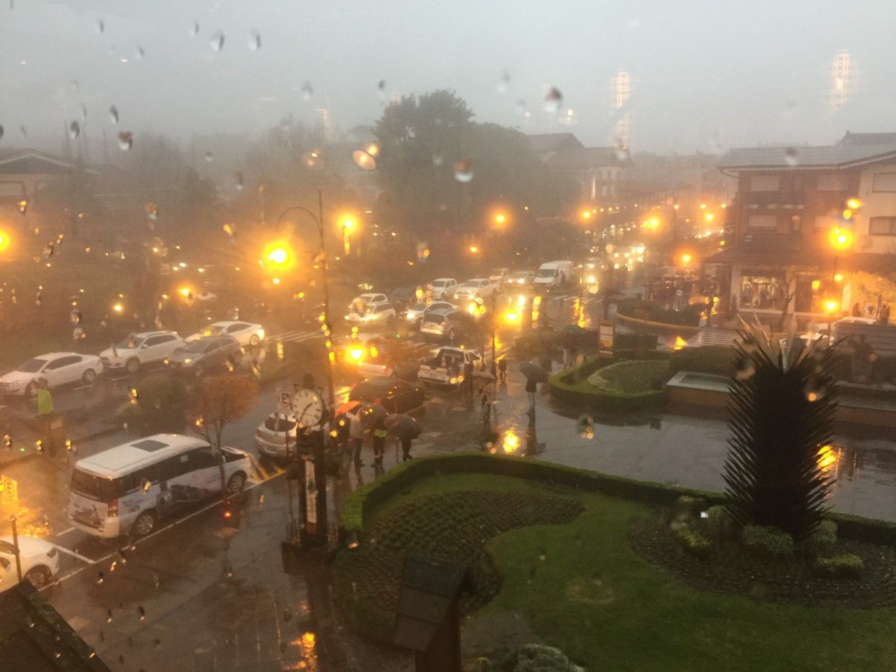 Uma rua da cidade na chuva à noite com muitos carros passando por ela.