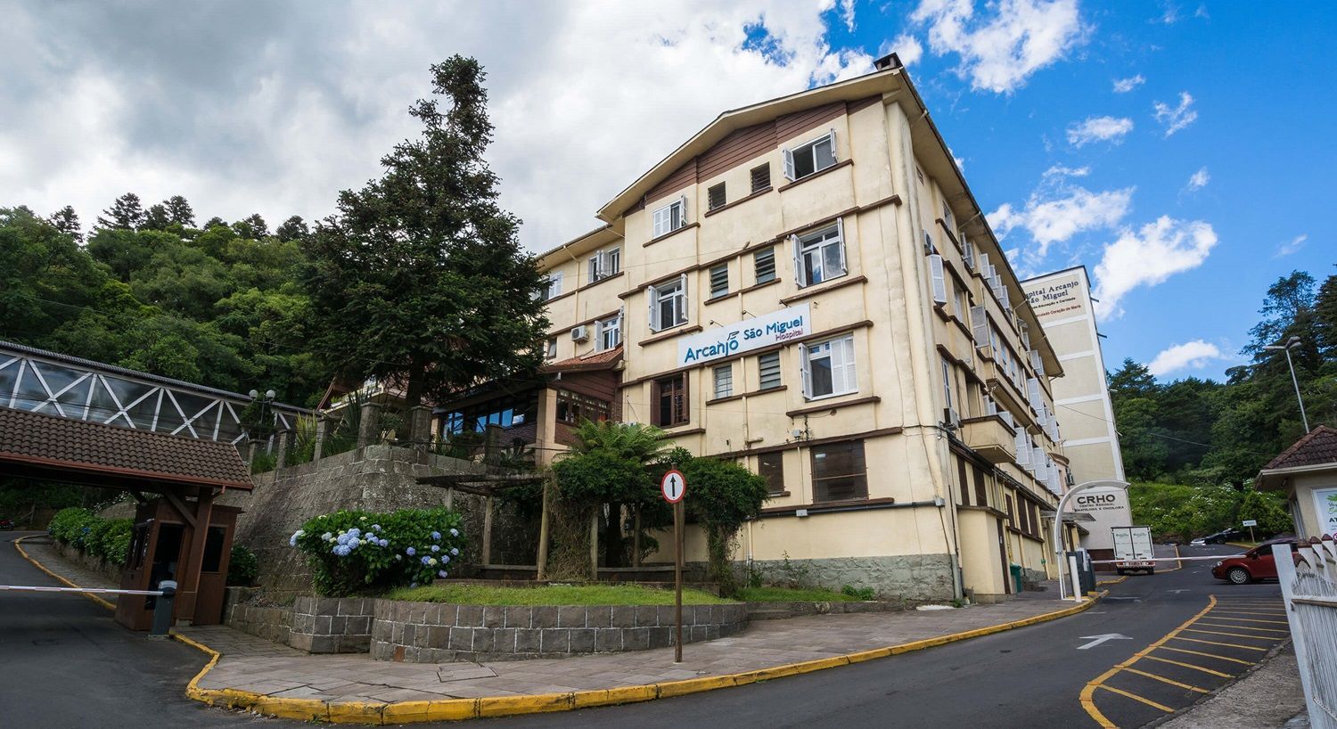 Um grande edifício está situado no topo de uma colina próximo a uma estrada.