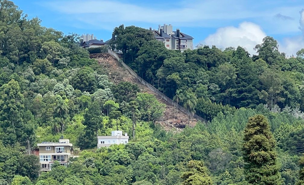 Uma casa está situada no topo de uma colina cercada por árvores.