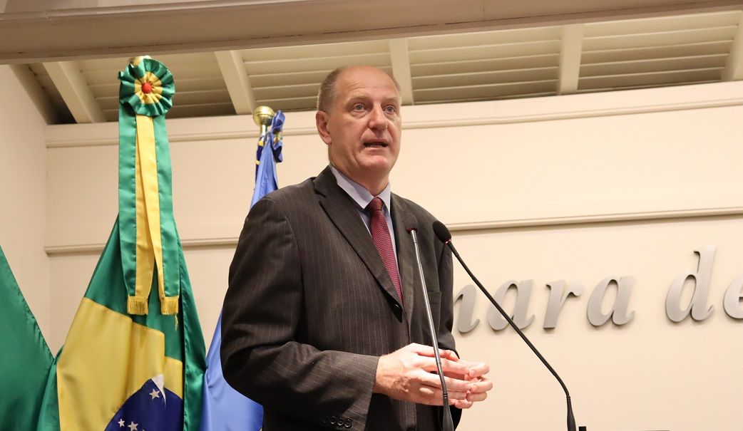 Um homem de terno e gravata está falando ao microfone