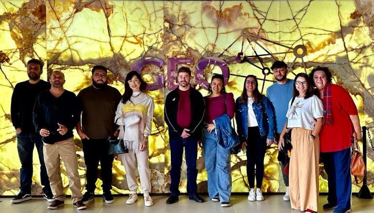 Um grupo de pessoas posa para uma foto em frente a uma parede.