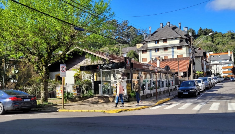 Uma fileira de carros está estacionada na beira de uma rua de uma pequena cidade.