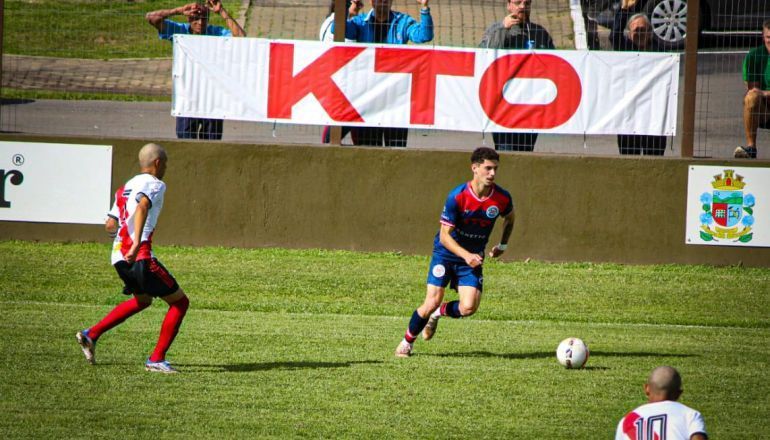 Um jogo de futebol está sendo disputado em um campo com uma faixa que diz kto.