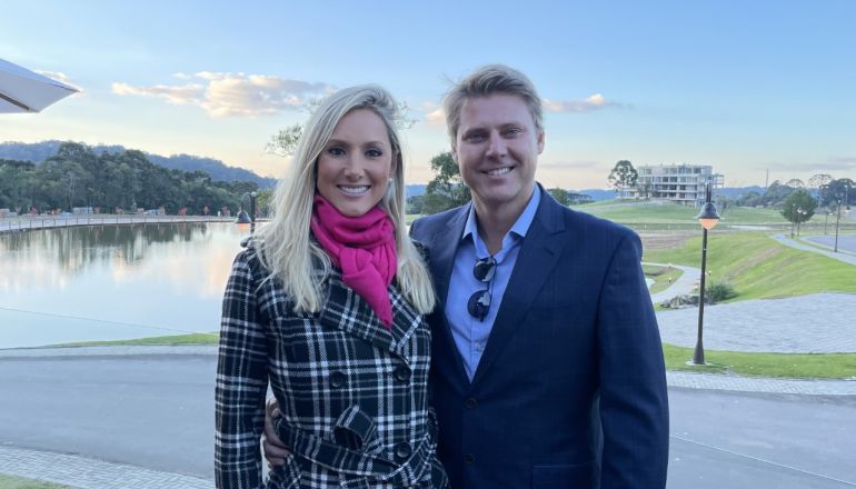 Um homem e uma mulher posam para uma foto em frente a um lago.
