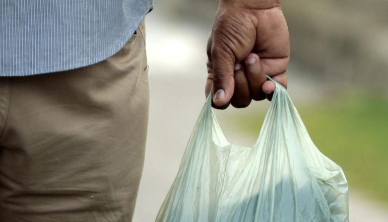 Um homem está segurando um saco plástico na mão.