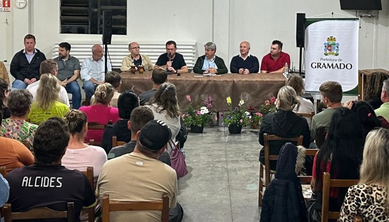 Um grupo de pessoas está sentado em cadeiras em frente a uma mesa.