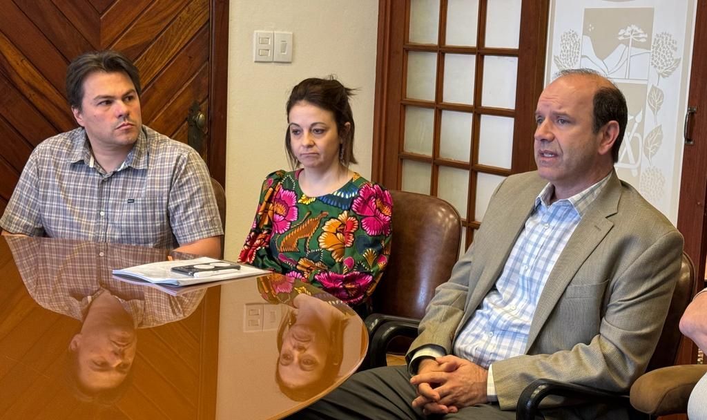 Um grupo de pessoas está sentado ao redor de uma mesa em uma sala.