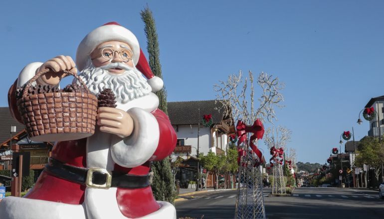 Uma estátua de Papai Noel segurando uma cesta em uma rua da cidade.