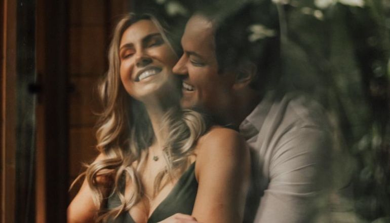Um homem e uma mulher estão sentados um ao lado do outro em frente a uma janela.