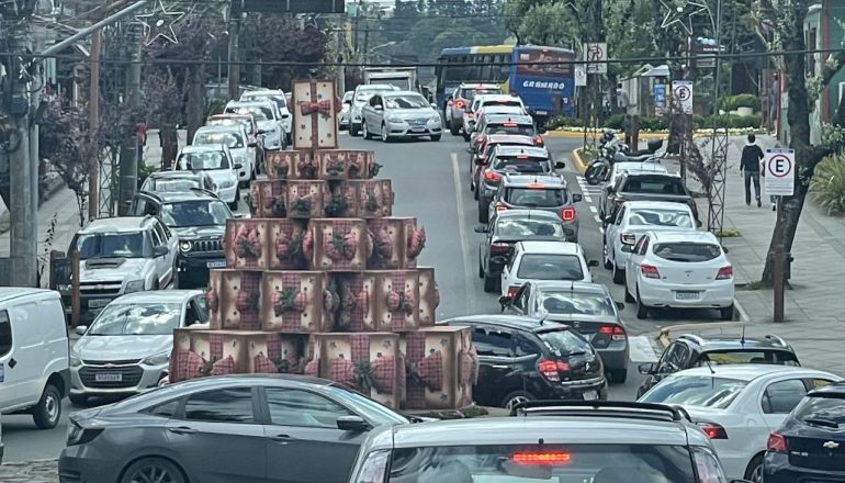 Um engarrafamento em uma rua da cidade com uma árvore de natal feita de latas.