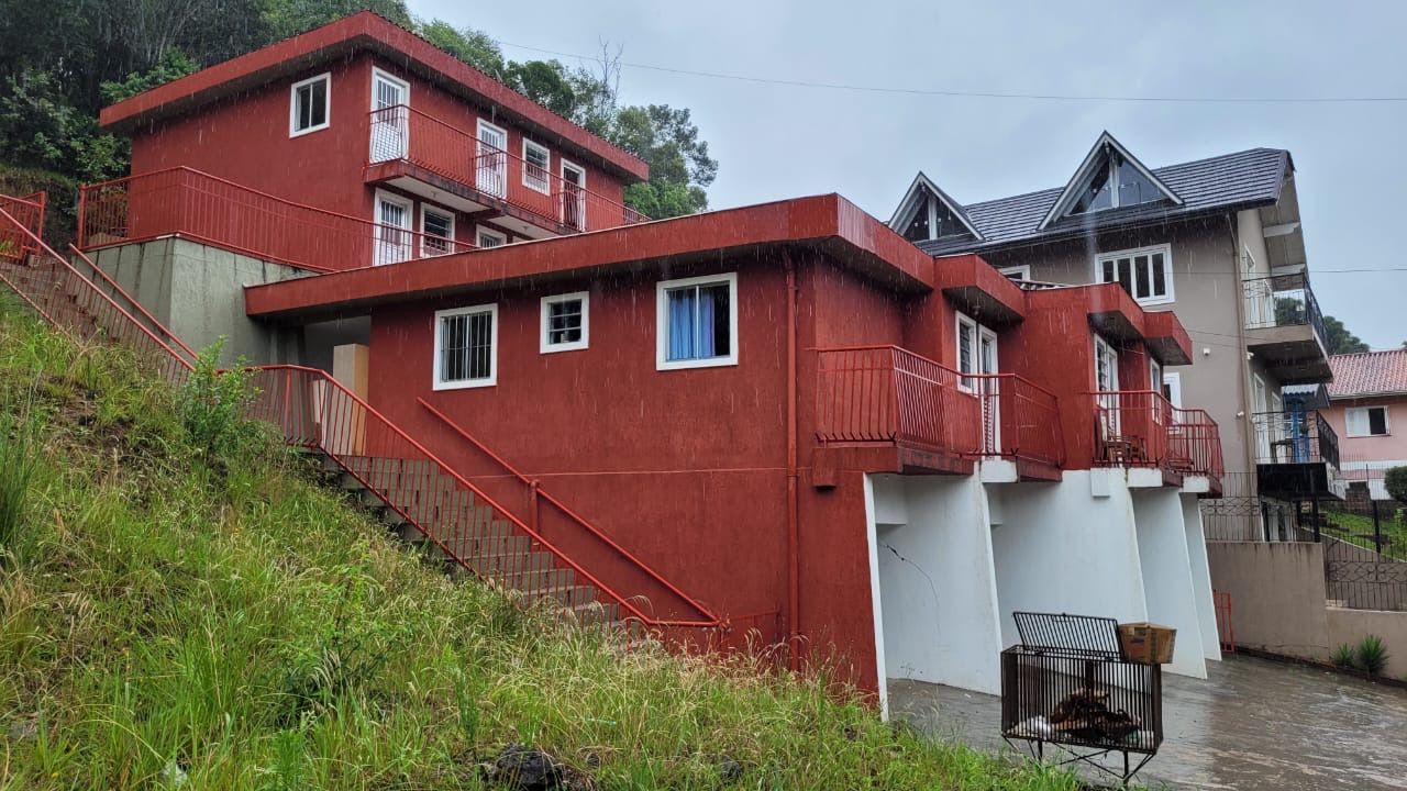 Um prédio vermelho com escadas que levam até ele está no topo de uma colina.