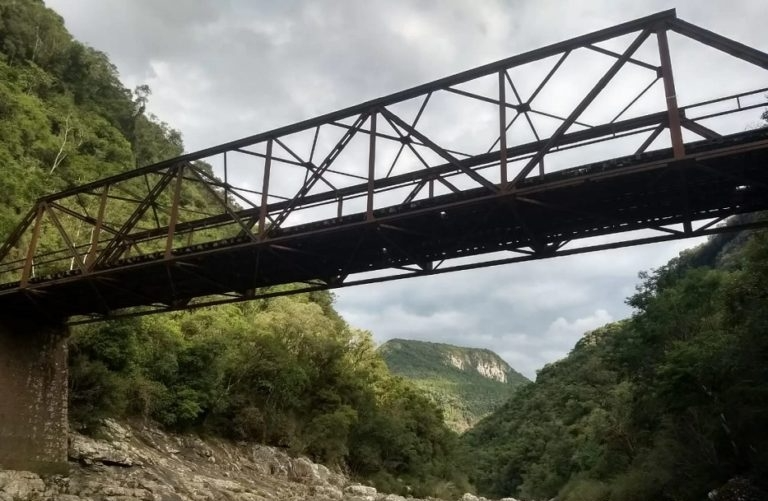Uma ponte sobre um rio com montanhas ao fundo
