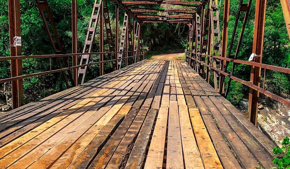 Uma ponte de madeira sobre um rio na floresta.