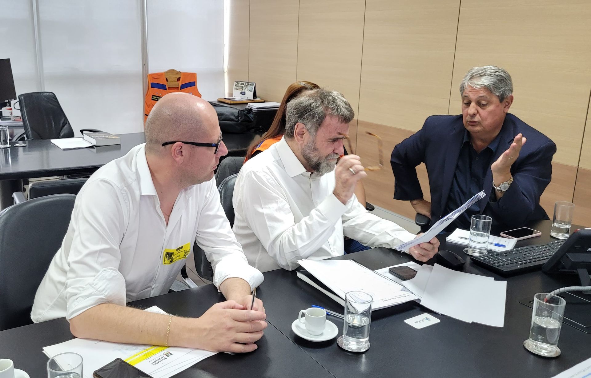 Um grupo de homens está sentado à mesa em uma reunião.