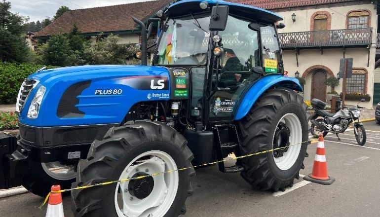 Um trator azul está estacionado na beira da estrada em frente a um prédio.