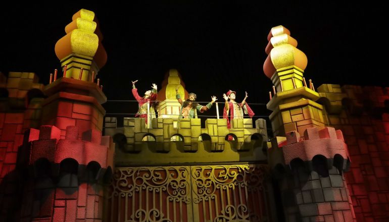 Um grupo de pessoas está no topo de um castelo à noite.