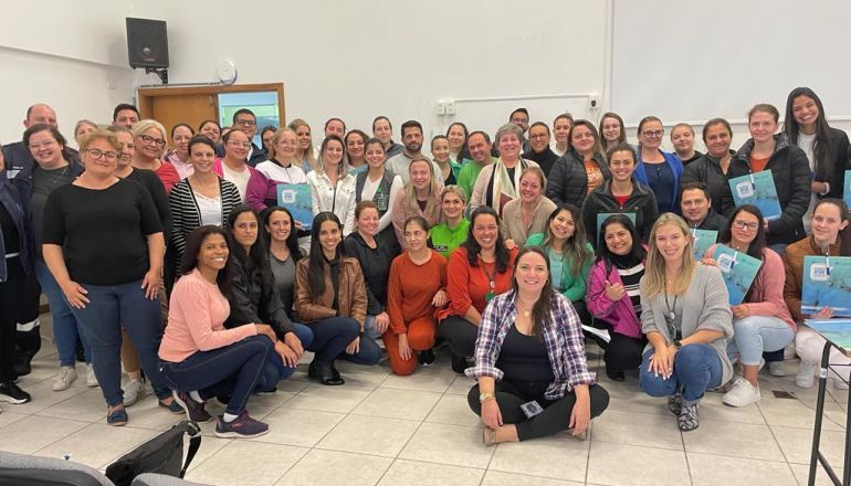 Um grande grupo de pessoas posa para uma foto em uma sala.