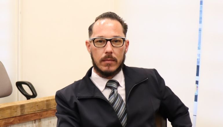 Um homem de terno e gravata está sentado em uma cadeira.