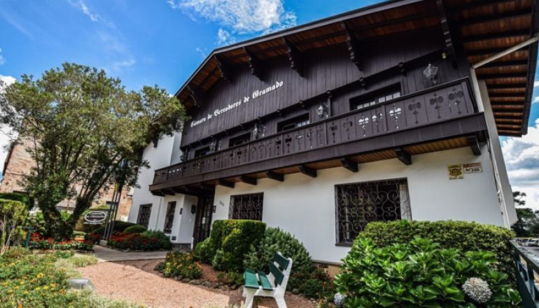 Uma grande casa branca com varanda e um carro estacionado em frente.