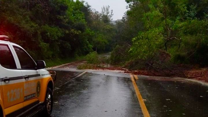 Um carro da polícia está estacionado na beira de uma estrada inundada.