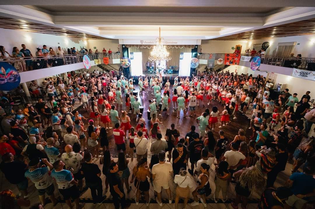 Uma grande multidão dança em uma grande sala.