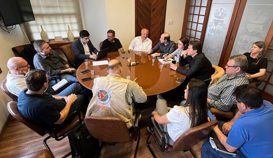 Um grupo de pessoas está sentado ao redor de uma mesa em uma sala de conferências.