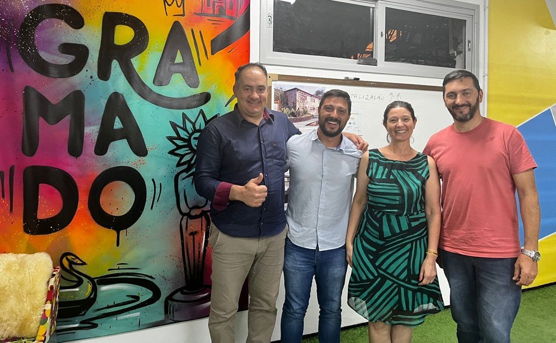 Um grupo de pessoas posa para uma foto em frente a uma parede grafitada.