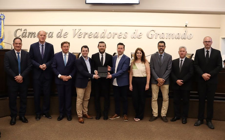 Um grupo de pessoas posando para uma foto em frente a uma placa que diz cam a de vereadores de gramado