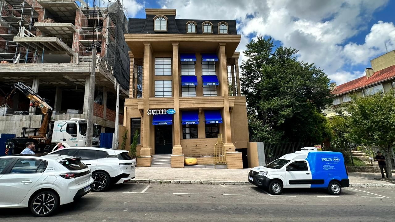 Uma van branca está estacionada em frente a um prédio em construção.