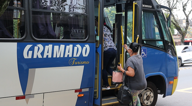 Uma mulher está descendo de um ônibus azul e branco.