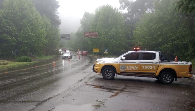 Um caminhão amarelo e branco está estacionado na beira de uma estrada molhada.