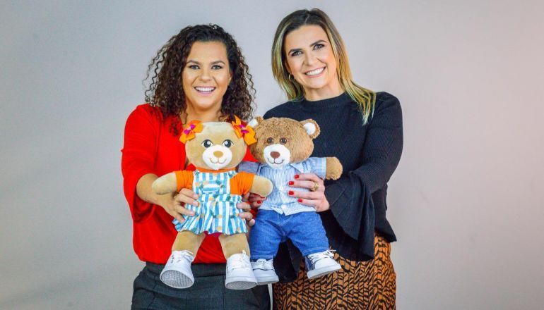 Duas mulheres estão segurando dois ursinhos de pelúcia nas mãos.