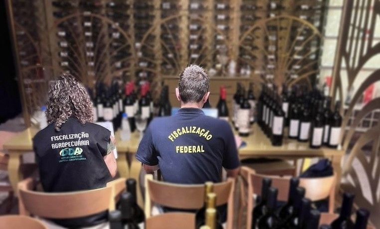 Um homem e uma mulher estão sentados à mesa com garrafas de vinho.