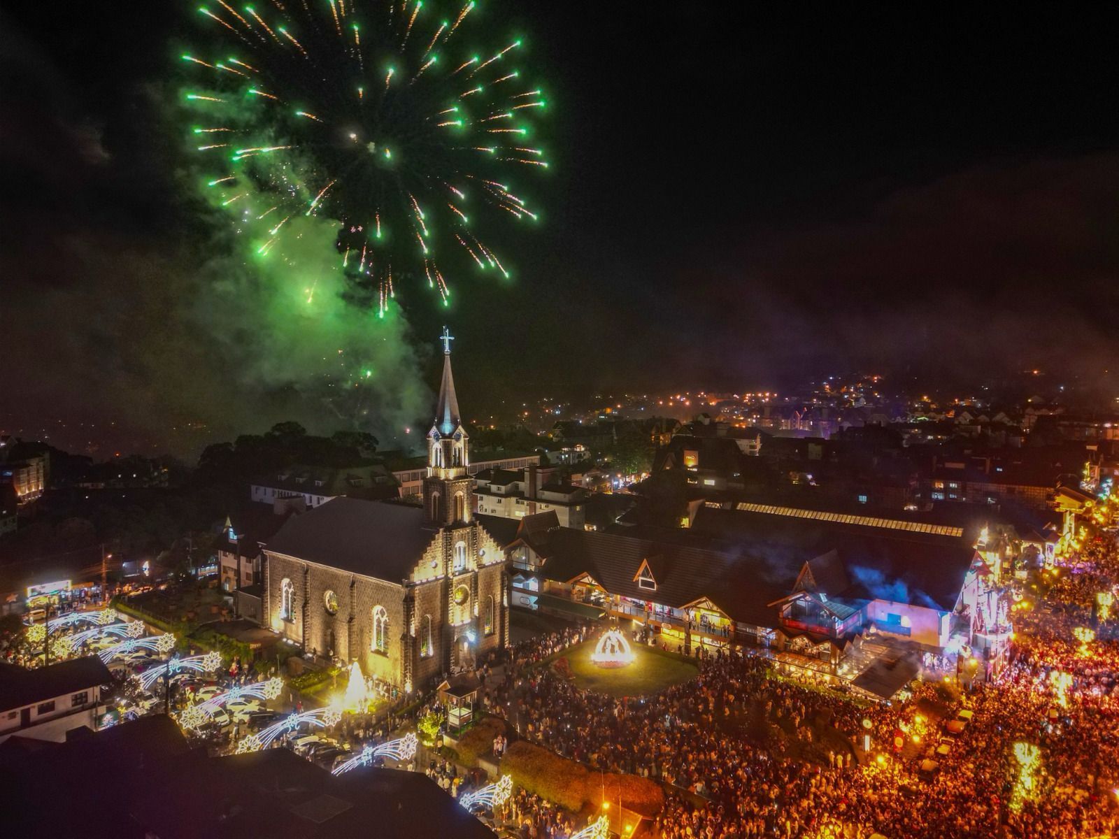 Uma vista aérea de uma igreja cercada por fogos de artifício à noite.