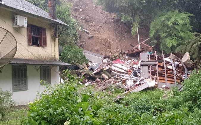 Uma casa está no topo de uma colina ao lado de uma pilha de escombros.