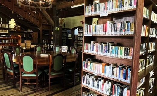 Uma biblioteca com mesa e cadeiras e estantes cheias de livros.
