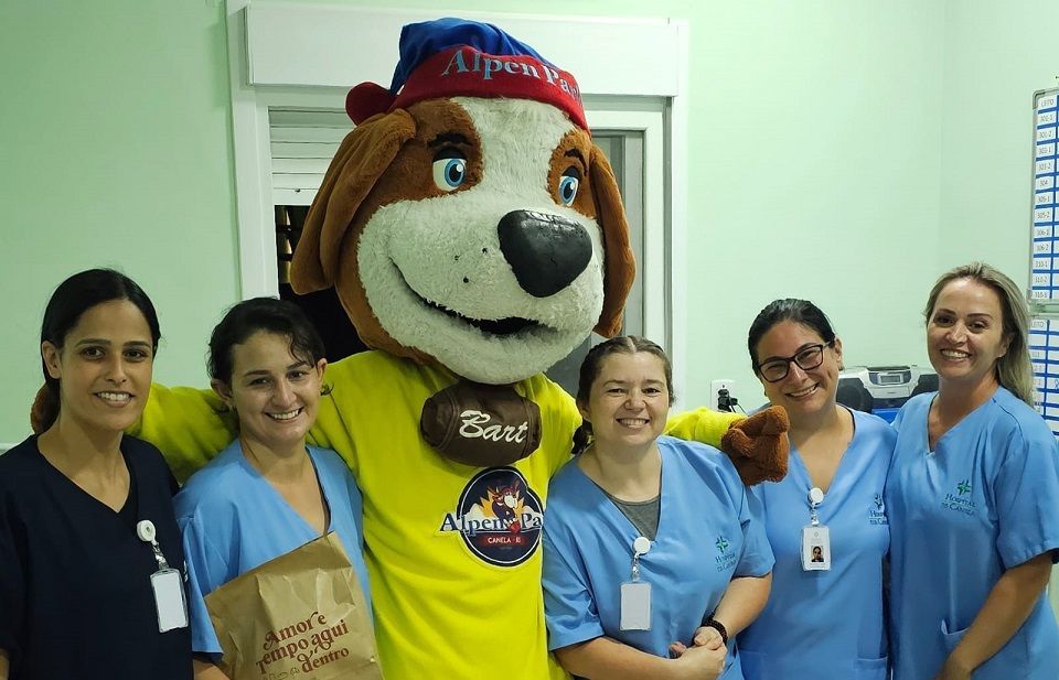 Um grupo de enfermeiras posa para uma foto com um mascote cachorro