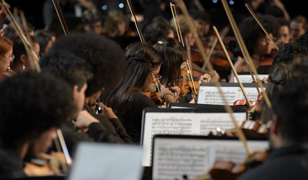 Um grupo de pessoas está tocando violinos em uma orquestra