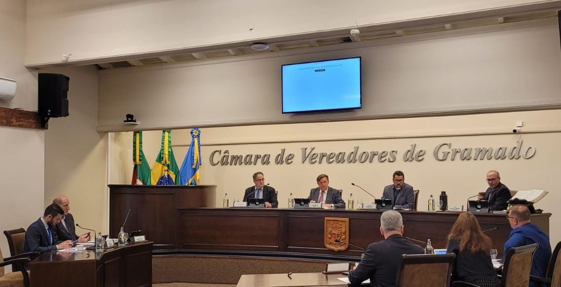 Um grupo de pessoas está sentado à mesa de uma sala.