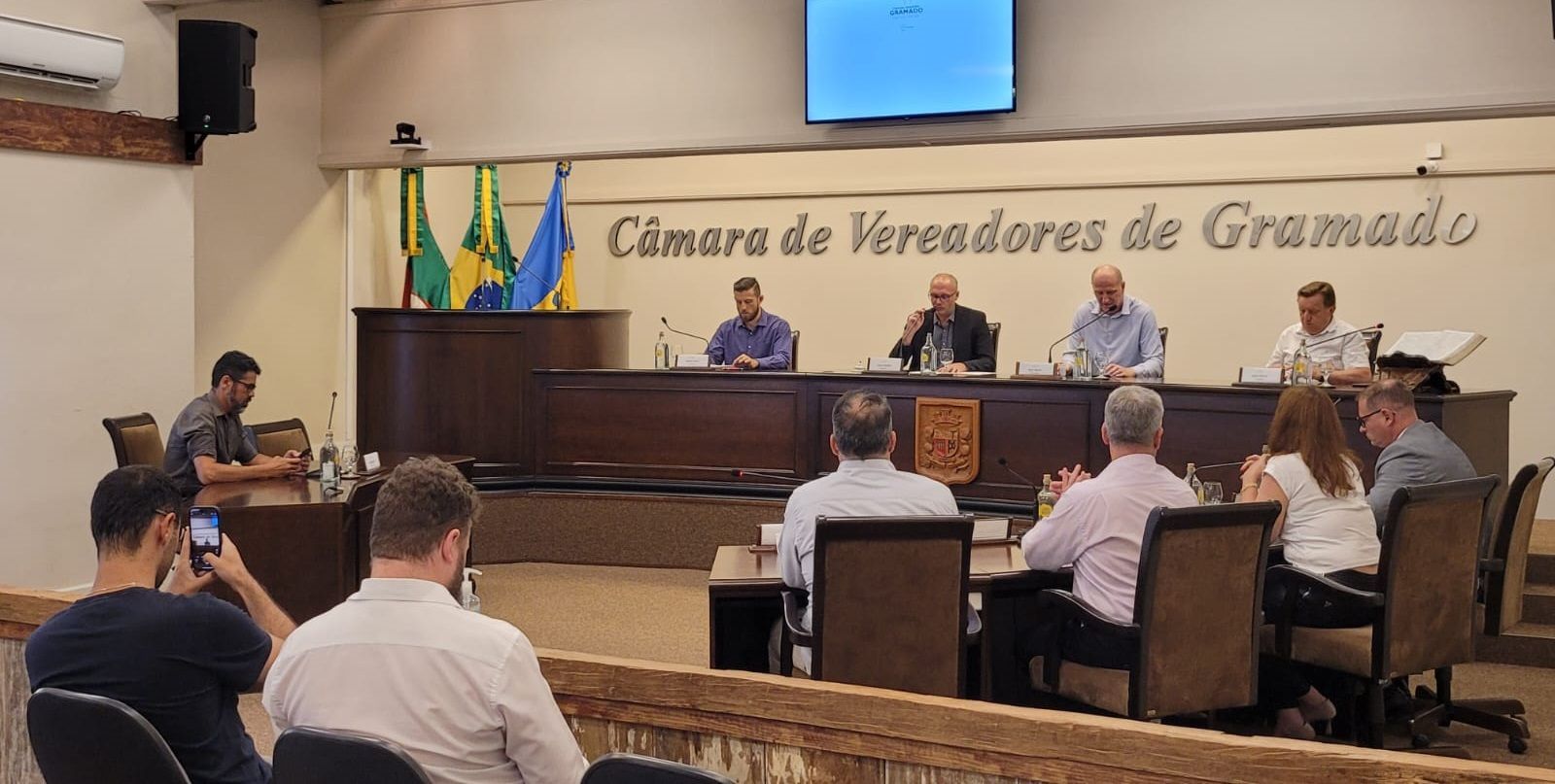 Um grupo de pessoas está sentado à mesa de uma sala.