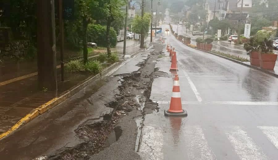 Uma estrada rachada com cones de trânsito ao lado.