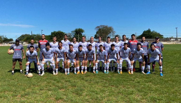 Um grupo de jogadores de futebol posa para uma foto em um campo.