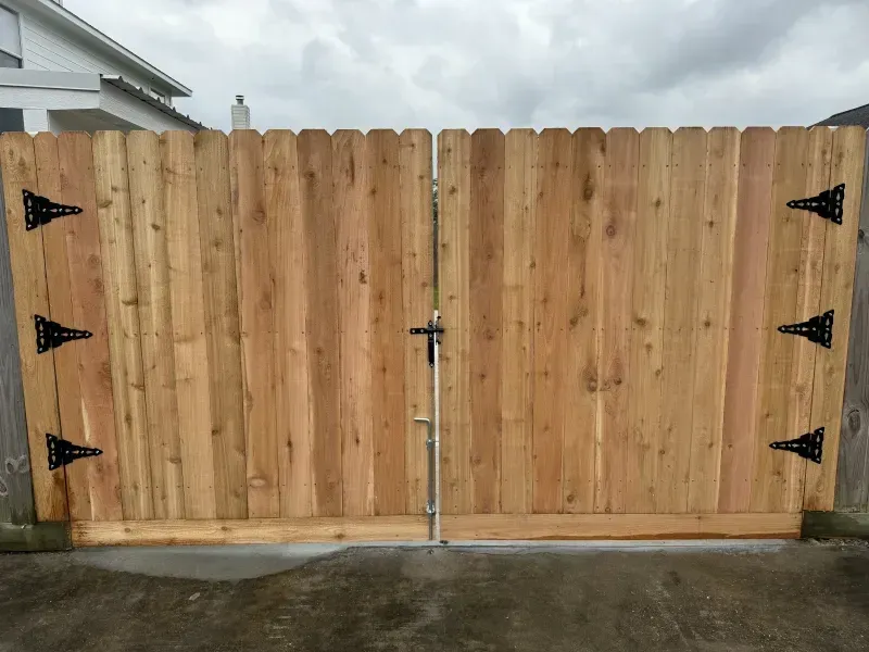 Wooden double gate with black hinges and a metal latch.