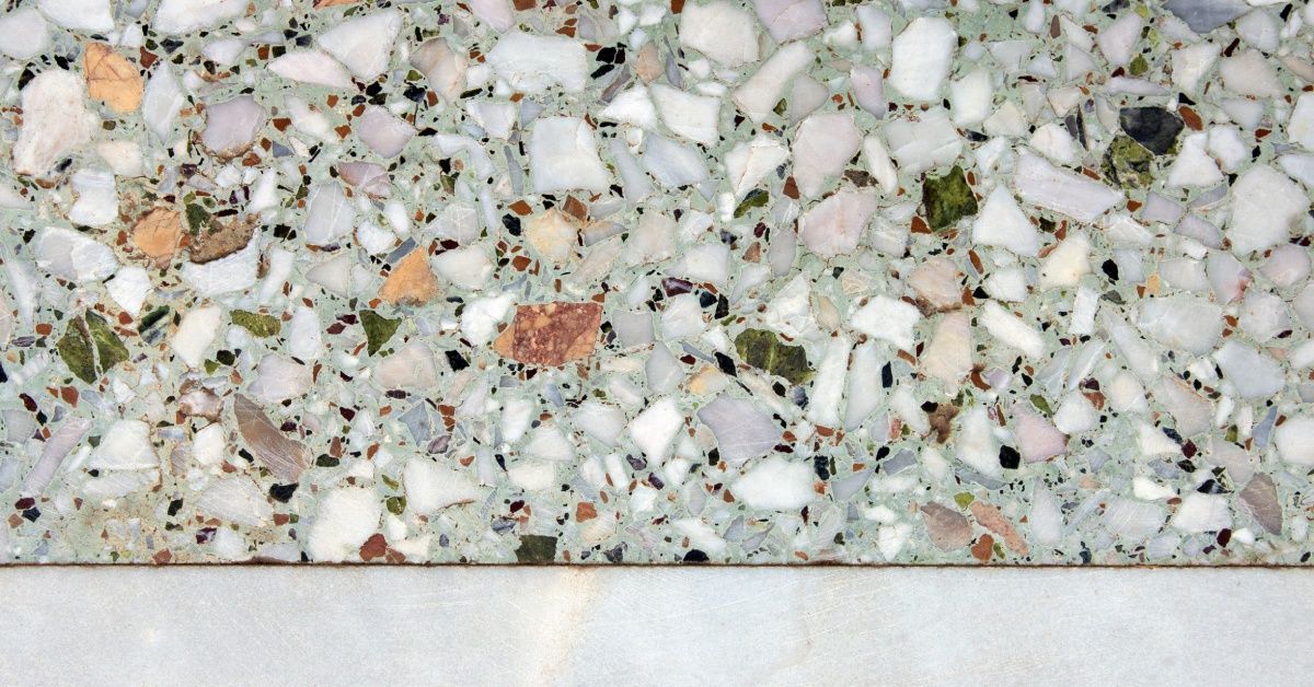 A close-up of a glass pebble flooring surface with a mosaic design. The pebbles vary in size and shape.